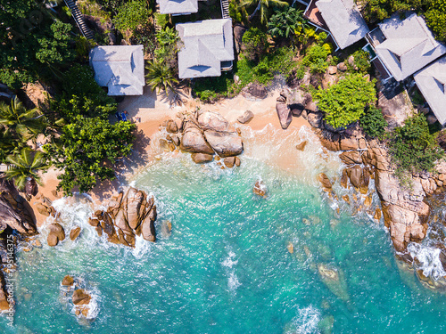 Aerial top down view of a beach with turquoise clean water rocks bungalows and huts in Koh Samui Thailand