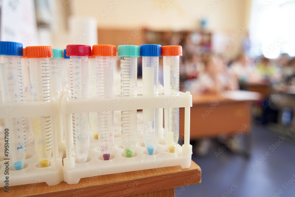 Vibrant lab test tubes in a rack, set against a blurred classroom backdrop. Perfect for educational and scientific themes.
