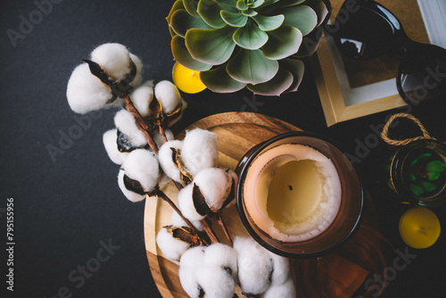Candles, wooden board, photo frame, cactus, cotton and sunglasses on a black background. Copy space