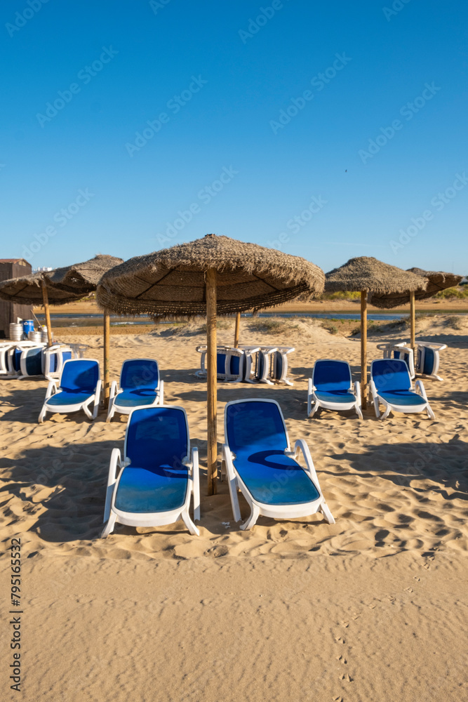 Beautiful summer landscape of the Spanish coast, Several sun loungers, sun loungers and parasol. Fine golden sand, sea view with horizon,blue sky, calm and relaxation. Inspiring vacation landscape.