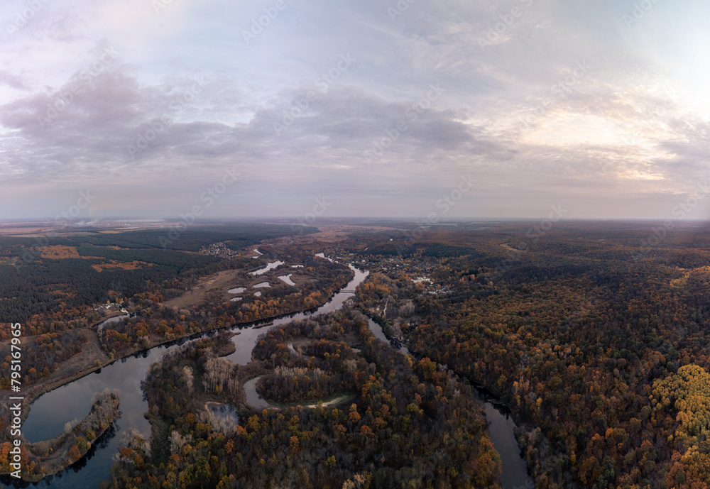 Aerial autumn river valley in colorful autumnal wooded countryside with evening sky