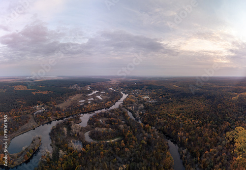 Aerial autumn river valley in colorful autumnal wooded countryside with evening sky