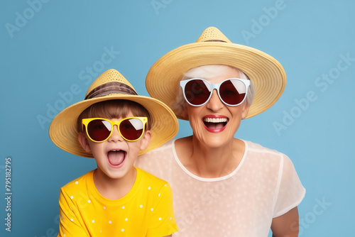 Happy Grandmother and Grandson Wearing Summer Hats and Sunglasses on Blue Background
