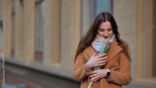 Portrait of a happy shade girl with a tulip in the background of the city in the cold season.