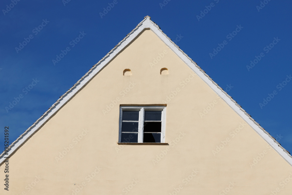 Gable of a house with a broken mullioned window under a blue sky in Wellenburg near Augsburg