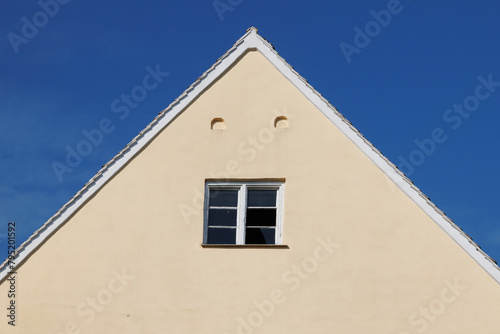 Gable of a house with a broken mullioned window under a blue sky in Wellenburg near Augsburg