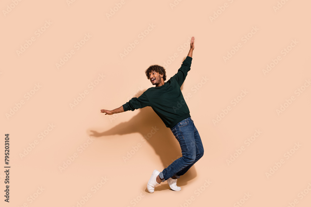 Full body portrait of nice young man dancing wear sweater isolated on beige color background