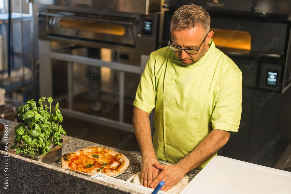 professional chef preparing pizza dough, an electric oven in the background. High quality photo