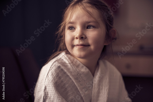 Little girl in bathrobe, smiling looking out the window