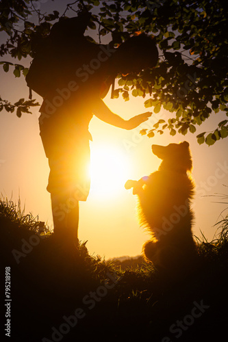 dog owner training tricks with his dog at sunset. Hiking with a pet.
