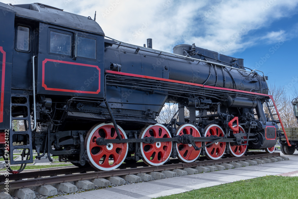 Naklejka premium A steam locomotive with a steam power plant using steam engines as an engine. Mainline passenger steam locomotive. Ancient railway transport. Transportation of goods by rail.