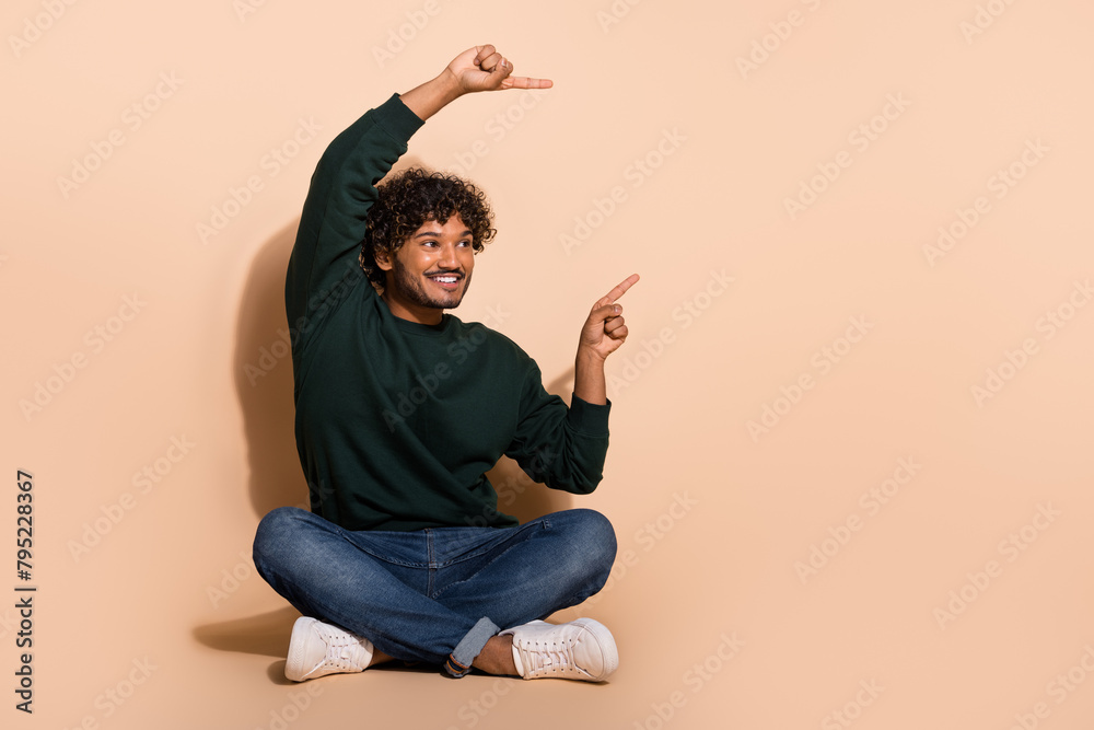 Full body portrait of nice young man point fingers empty space ad wear sweater isolated on beige color background Full body portrait of nice young man point fingers empty space ad wear sweater isolated on beige color background