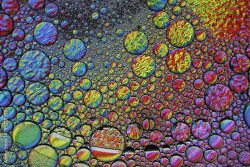 Burbujas de agua y jabón flotan sobre una superficie acuática, con luz superficial sobre un fondo bokeh, formando un diseño original multicolor y abstracto para fondos photo