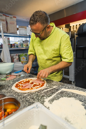 vertical shot of a man cook adding meat and seasonings to prepare pizza. High quality photo