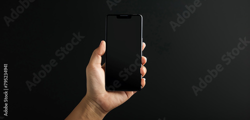 The allure of a hand holding a blank smartphone screen against a black background, symbolizing the endless possibilities and potential of technology. 