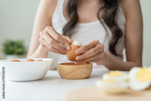 woman holding boil egg and pilling off eggshell