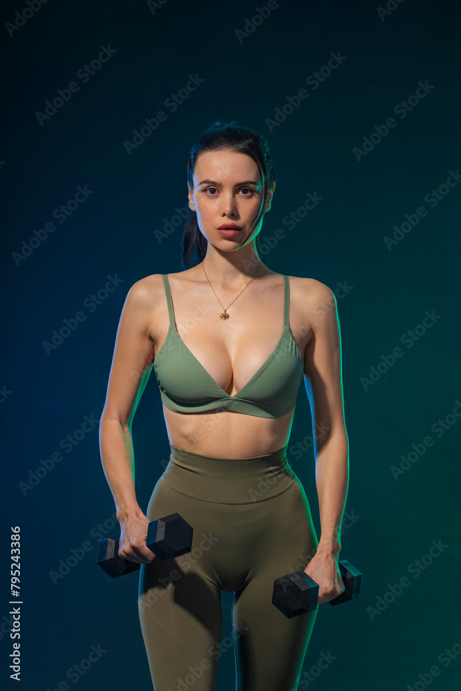 Obraz premium Sporty fit woman, athlete with dumbbells make fitness exercises on neon background. Download cover for music collection for fitness classes. Sports recreation. Beautiful black young woman.