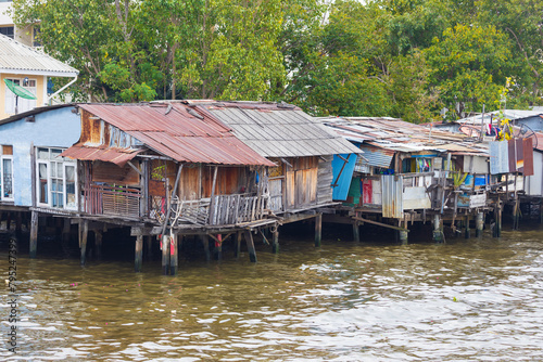 View on collapsing wooden residential slums on stilts where people live on the Chao Phraya River in Bangkok, Thailand