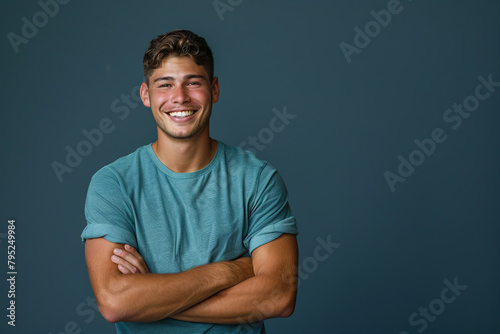 Smiling, handsome young man with arms crossed. Joyful, cheerful male laughing with hands folded in a studio setting photo