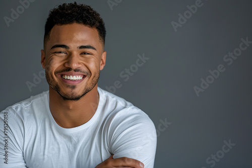 Smiling, handsome young man with arms crossed. Joyful, cheerful male laughing with hands folded in a studio setting photo