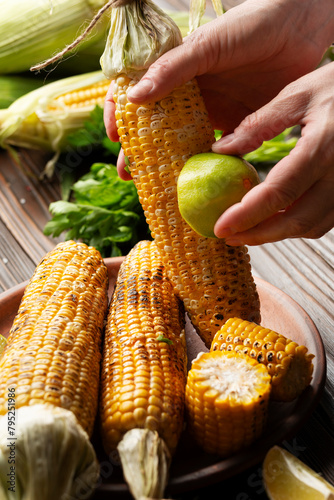 Obraz na płótnie Female hands rubbing a roasted sweet corn cob with lime w salonie