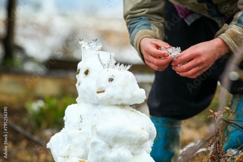 The snowman is not just built by children; adults too find joy and relaxation in contributing to his creation.
 photo
