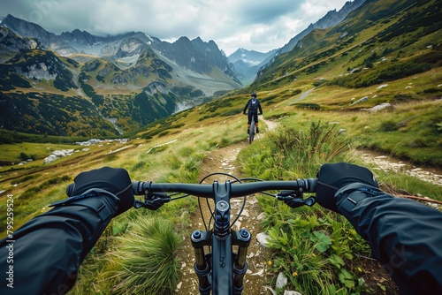 A first-person perspective captures the thrilling experience of mountain biking along a narrow trail in a picturesque mountainous region. photo