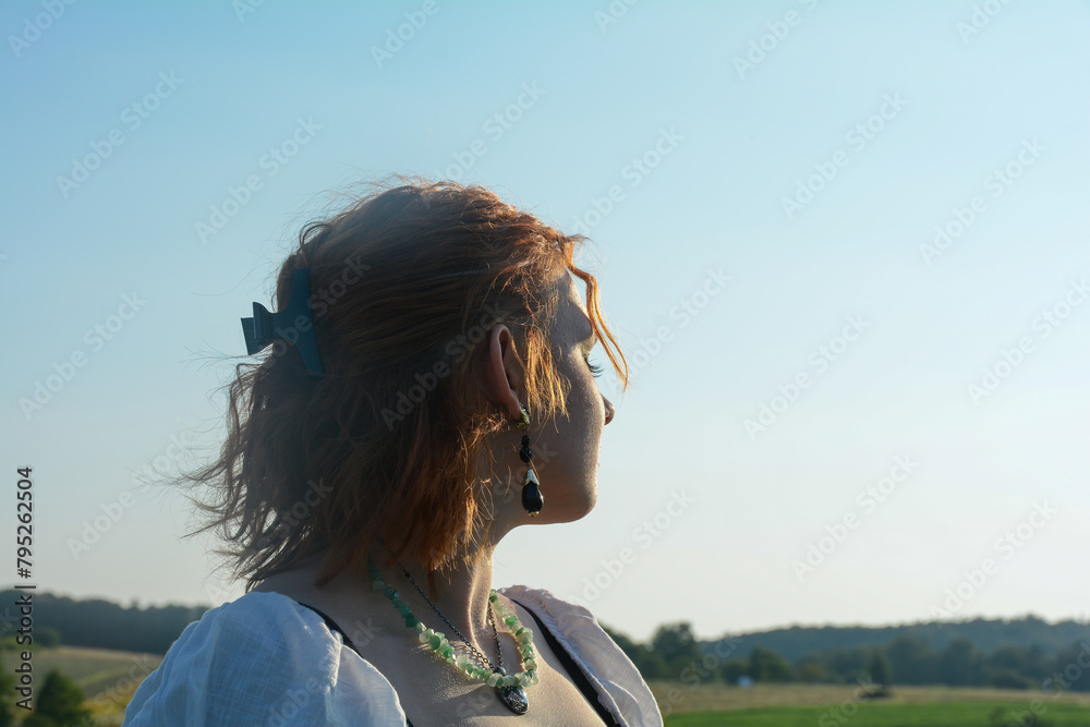 Young woman stands in nature and enjoys the sun Young woman stands in nature and enjoys the sun