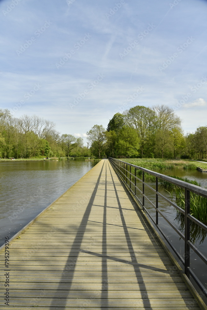 La passerelle longeant au raz de l'eau l'étang principal au Vrijbroekpark à Malines La passerelle longeant au raz de l'eau l'étang principal au Vrijbroekpark à Malines
