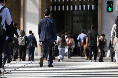 オフィス街の横断歩道を渡るビジネスマン photo