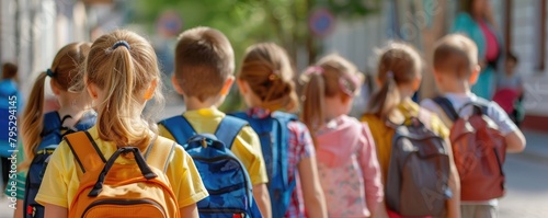 A group of young students with bright backpacks standing in a line, portraying the concept of education and friendship among schoolchildren. © Milan