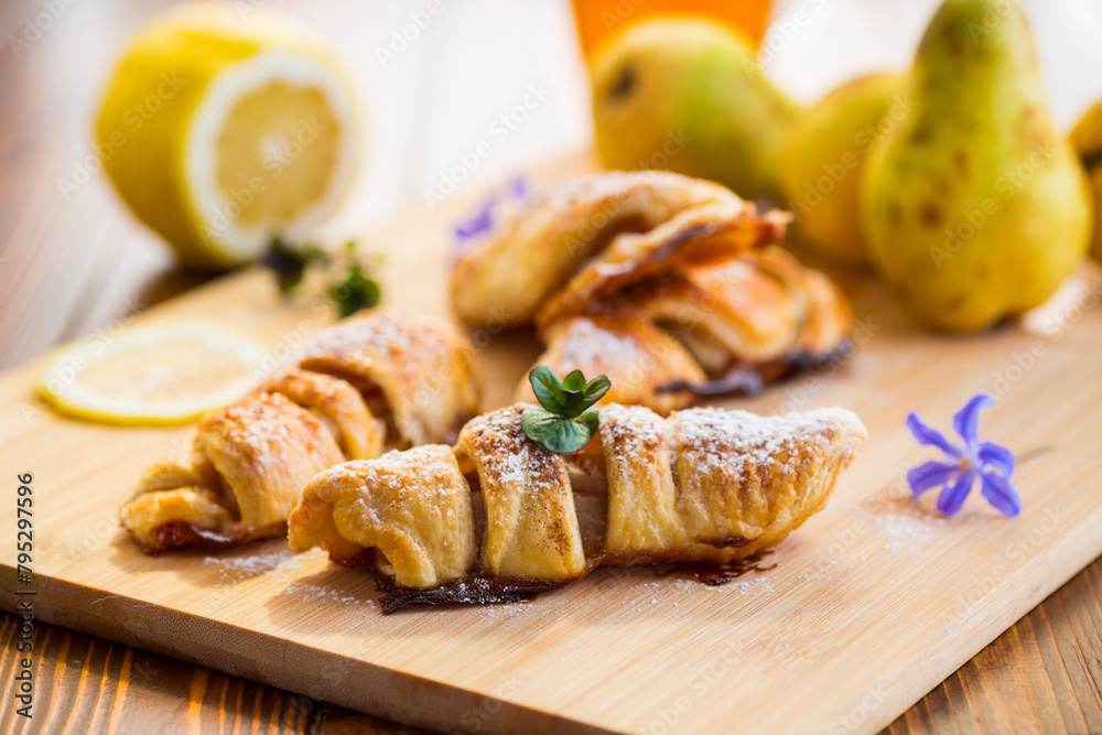 Sweet pastries, puff pastries with pears, on a wooden table