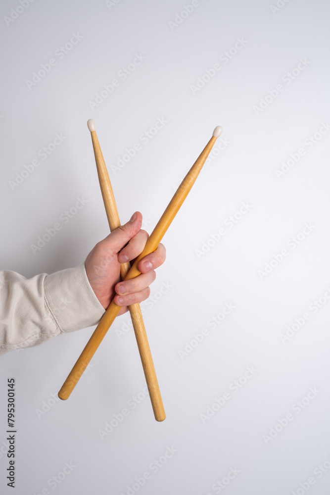 Man is holding wooden drumsticks on a light background. Music and hobby concept Man is holding wooden drumsticks on a light background. Music and hobby concept