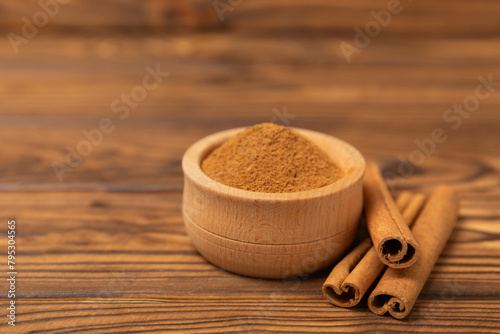 Cinnamon sticks on a textured wooden background. Cinnamon roll. Spicy spice for baking  desserts and drinks. Fragrant ground cinnamon. cinnamon powder Close-up. Place for text. copy space