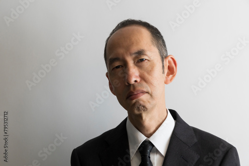 睨むスーツ姿の日本人の中年男性のポートレイト