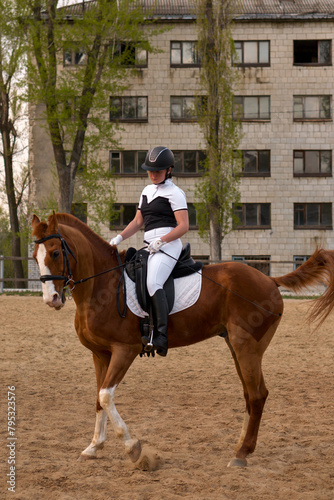 Focused dressage rider on chestnut horse in urban setting