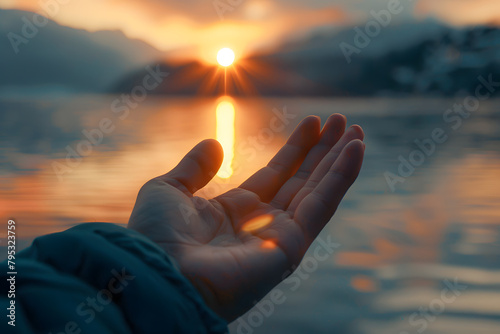 Close-up of intertwined fingers in a Zen gesture, with a blurred background of a sunrise over a tranquil lake