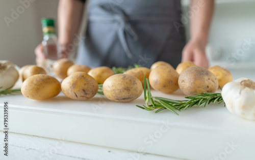 Raw potatoes with herbs and garlic on a white cutting board. Healthy eating background