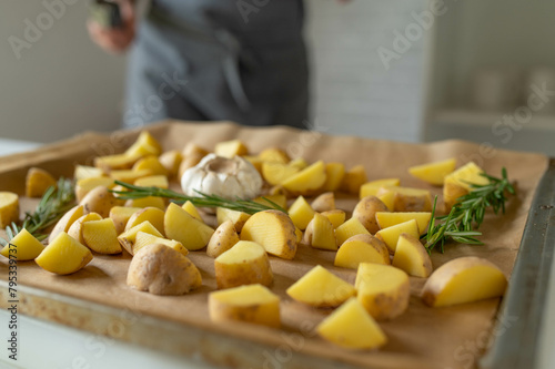 Woman preparing fresh cubed potatoes on a baking sheet for making roasted potatoes