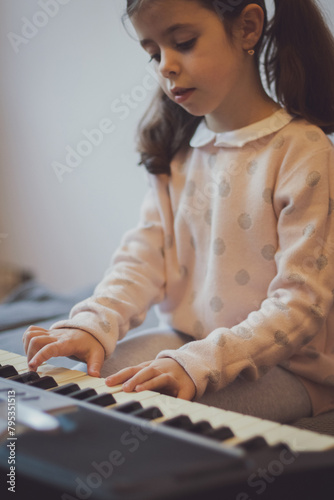 A little girl plays the electric piano.