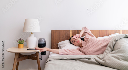 Portrait of beautiful young sexy asian woman tried in the morning bedding linen mattress in white bed room modern apartment. Cute asia girl stretching snooze alarm awake from sleep, good night sleep