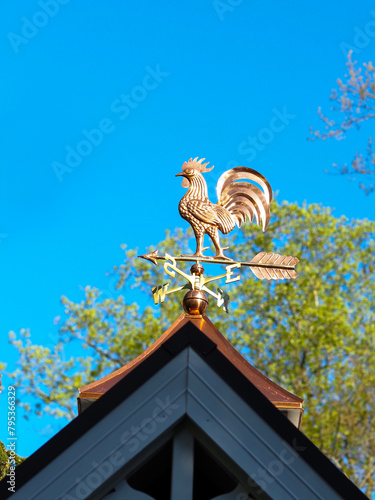 Copper rooster weathervane against blue sky photo