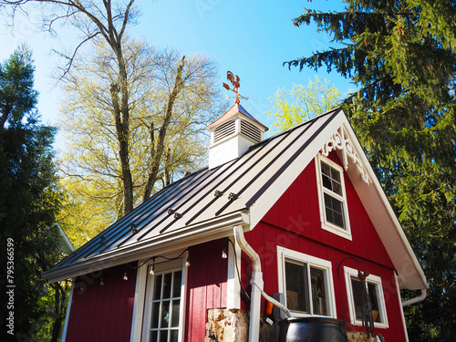 Copper rooster weathervane and cupola on red shed or barn with dark metal roof