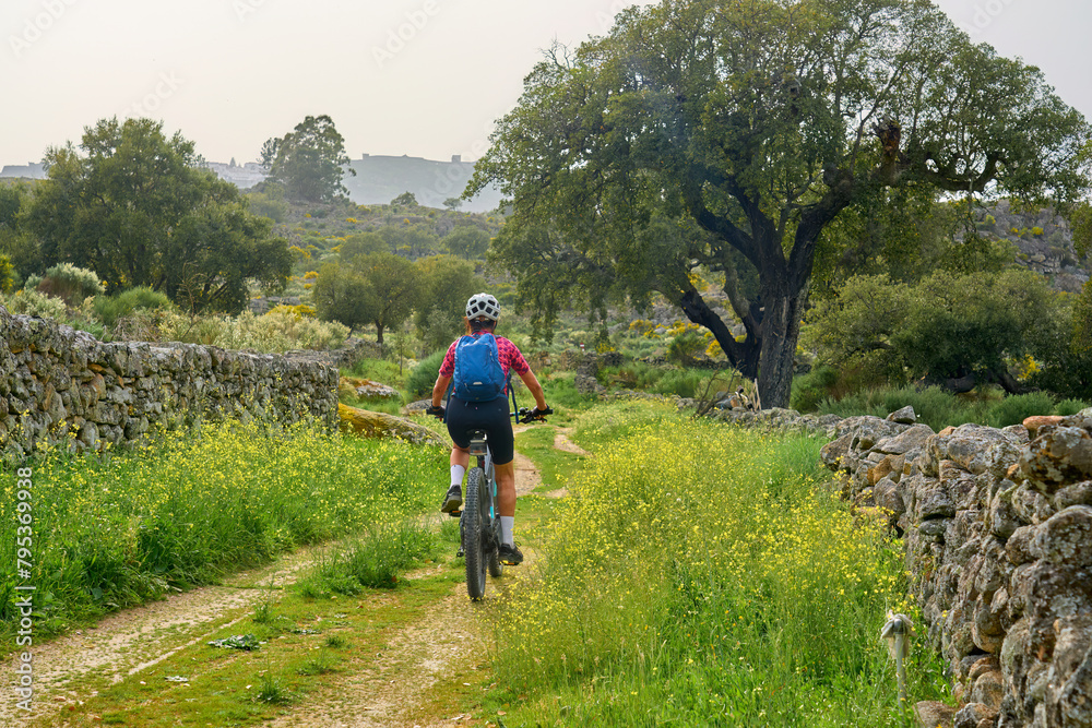 Obraz premium active senior woman cycling with her electric mountain bike in the rough landscape of National Parc Serra de São Mamede near Marvao in central Portugal, Europe