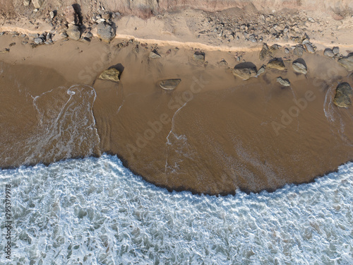 AERIAL TOP DOWN: Ocean waves gently lapping along an empty stretch of sandy beach. Stunning pattern formed by the waves spilling over wet sandy shoreline. Beautiful Atlantic coastline in Portugal.