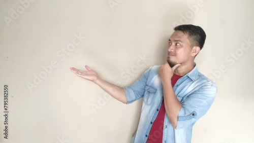 Adult Asian man smiling with left hand pointing to his opened right hand palm photo