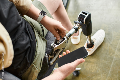 A businessman with a prosthetic leg siting and checking his cell phone.