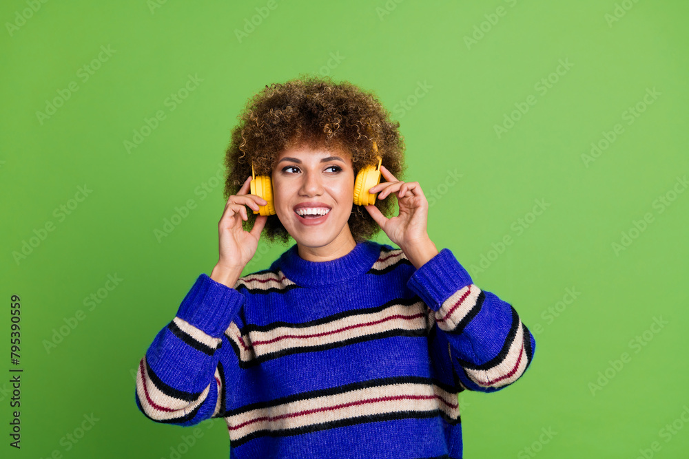 Photo of cheerful pretty woman wear blue striped trendy clothes listen music look empty space isolated on green color background Photo of cheerful pretty woman wear blue striped trendy clothes listen music look empty space isolated on green color background