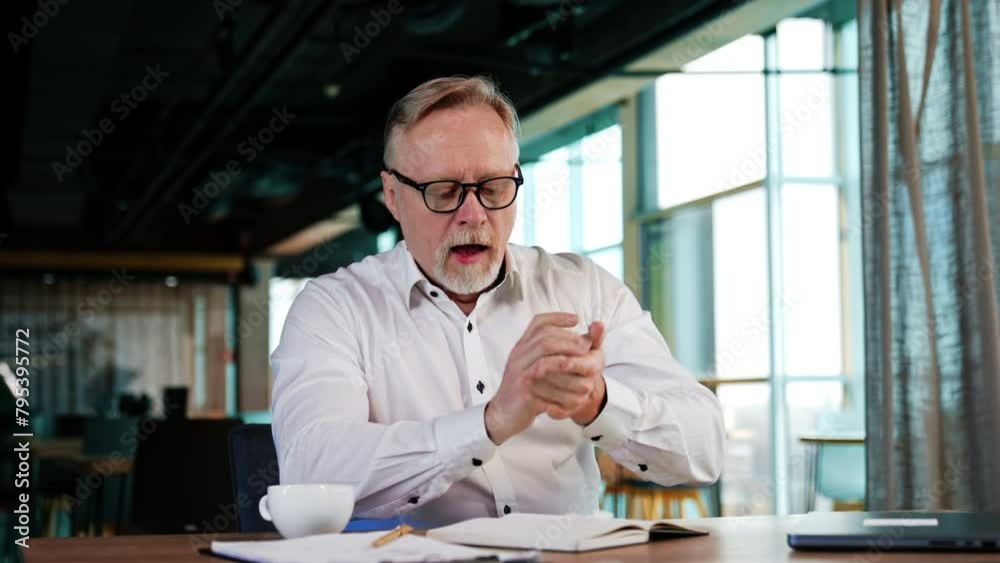 Senior man in white shirt pulls the pages out of his paper book. Man rolls the papers in a ball and throws them backwards.