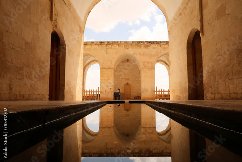 Water in a pond, pool reflecting the arches, vaults and doors of the Sultan Isa Medrese, Madrasa, Zinciriye Medrese in the old town of Mardin, Turkey photo